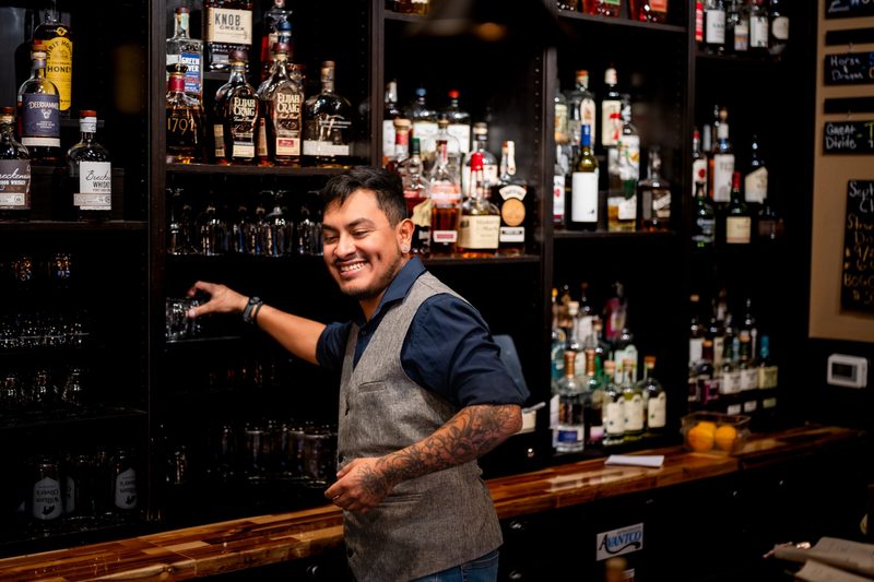 A bartender smiling while stocking glasses