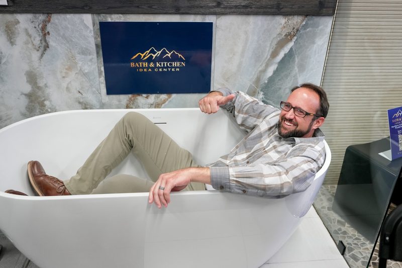 An attendee relaxing in a showroom bathtub