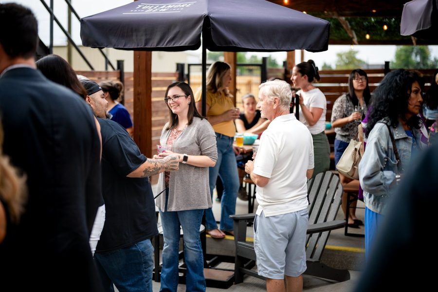 Attendees chatting under patio umbrellas